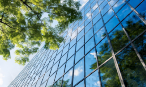 Image of a skyscraper and tree branches with tree reflecting off the glass.